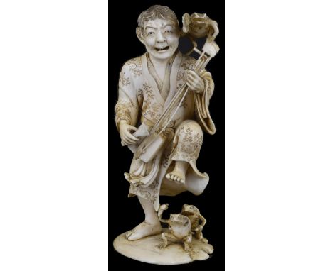 ˜A JAPANESE IVORY OKIMONO OF A MUSICIAN, MEIJI PERIOD (1868-1912) carved playing a samisen and hopping over the toads at his 