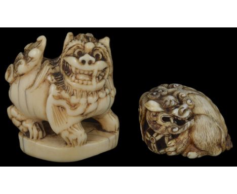 ˜TWO JAPANESE IVORY NETSUKE OF SHISHI, 18TH AND 19TH CENTURY one a study of a shishi crouched and curled around a pierced bal