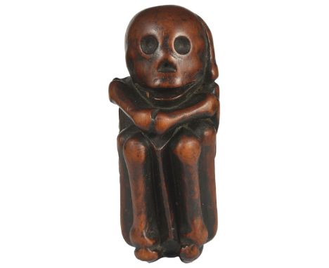 ˜A JAPANESE EBONY NETSUKE OF A SKELETON, LATE EDO PERIOD, CIRCA 1820 folded into a foetal position for burial according to an