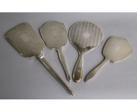 Four assorted 20th century silver hand mirrors including three engine turned and one with foliate engraving, largest 37.8cm.