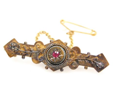 A Victorian brooch, set with a single ruby, yellow metal, stamped 15ct, with safety chain, 3.1g.