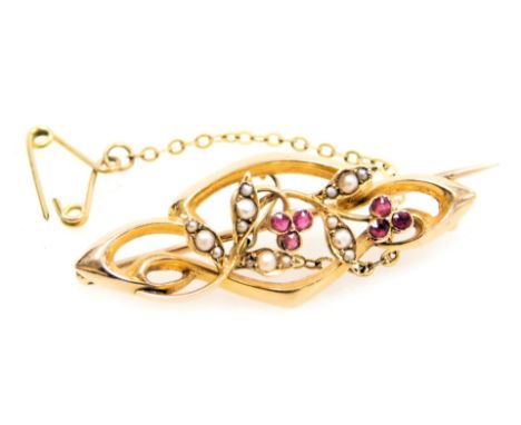 An Edwardian ruby and seed pearl brooch, in a scrolling floral and foliate design, in yellow metal, stamped 15ct, with safety