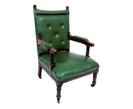 A Victorian oak armchair, upholstered in button back green leatherette, raised on turned legs, brass capped on castors, 63cm 