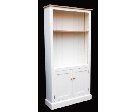 A light oak pine and grey painted cupboard bookcase, with a single shelf, over a pair of cupboard doors, raised on a plinth b