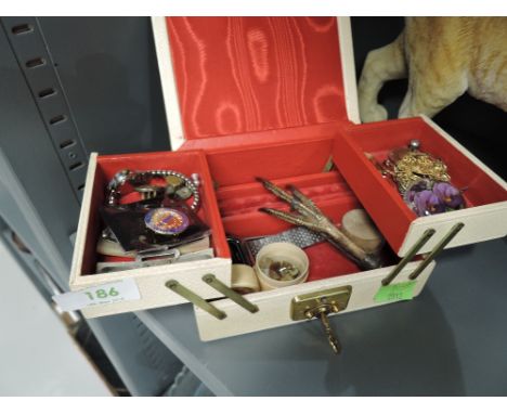 A small vintage jewellery box containing a small selection of costume jewellery including mother of pearl buckle, chicken foo