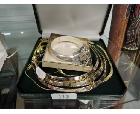 A white metal hinged bangle stamped 925 having engraved scroll decoration and a white metal shield and charm bracelet