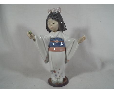 A Lladro figure depicting a young girl holding a flower 19.5 cm (h)