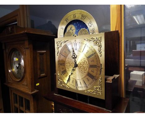 A contemporary grandmother style clock in a dark mahogany finished case, the Westminster chiming movement behind a brass arch