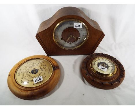 Two circular cased wall mounted aneroid barometers, one having a turned and carved surround, cream enamel chapter ring and op