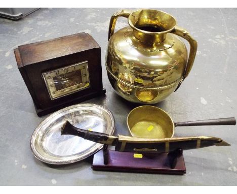 A good mixed lot to include an oak cased Art Deco mantel clock, a Kukri knife in scabbard on stand, a brass skillet, a plated