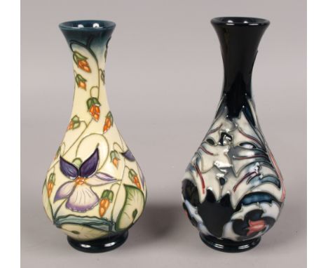 Two Moorcroft baluster vases, one decorated by R. J. Bishop along with a similar ink ground example both 16.75cm tall.Conditi
