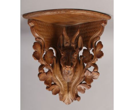 An early 20th century Black Forest corner bracket shelf, carved with the head of a Deer and acanthus leaves.