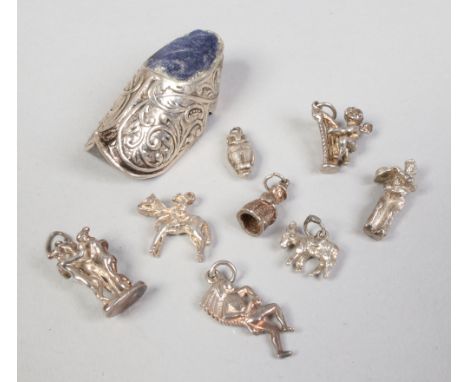 A collection of silver charms and a continental silver Dutch dog pin cushion.