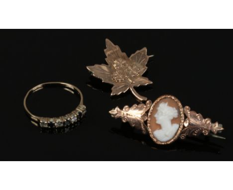 A 9ct gold ring set with blue and white paste stones, size O, along with two antique gold plated sweetheart brooches.