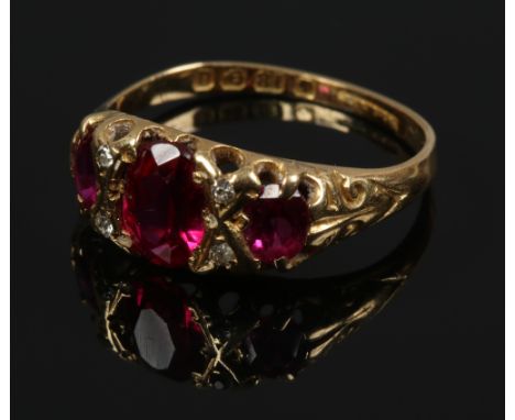 An Edwardian 18ct gold ring, set with three faceted red stone, boarded by diamonds, assayed Birmingham 1903, size M1/2.