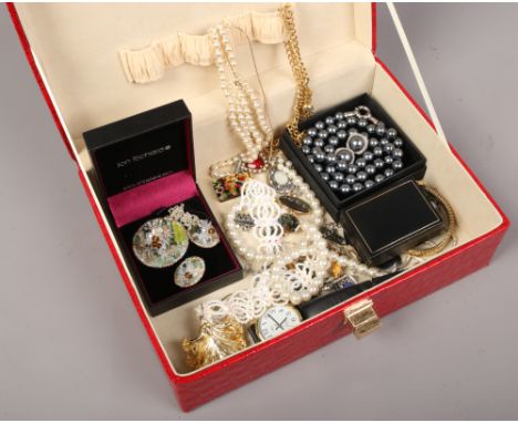A red leather effect jewellery box containing various dress jewellery including simulated pearl necklaces, wrist watches, pen