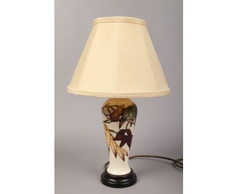 A Moorcroft ivory ground high shouldered table lamp decorated with Autumnal trailing foliage with cream fabric shade.