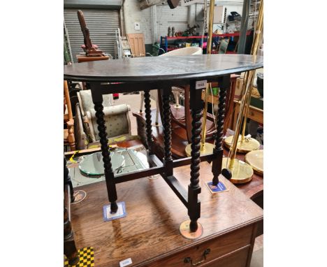 A 1920s oak folding table on bobbin turned supports. 