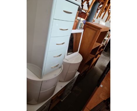 A white dressing table, two white bedside cabinets, a white chest of drawers, a white framed mirror and a cane bedside table.