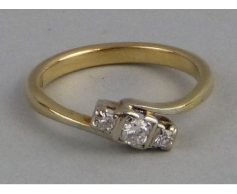 A three stone diamond ring, the three stones set in line at an angle on 18ct gold shank with offset shoulders, size M