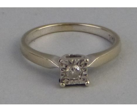 A solitaire diamond ring, the single stone illusion set in a square surround on 9k white gold shank, size J