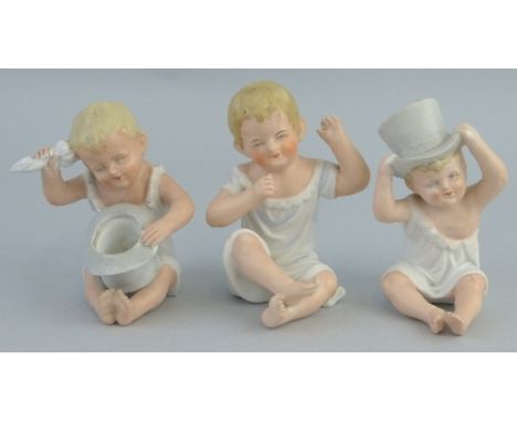 A pair of continental bisque piano babies, each depicted seated playing with a top hat, 11cm high and another similar bisque 
