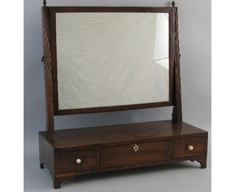 A 19th Century mahogany toilet mirror, the oblong plate on reeded uprights with metal acorn finials on box base with three dr