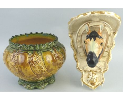 A wall bracket, as a horses head, horseshoe and other hunting motifs on a textured white and gilt ground, 21.5cm high and a m