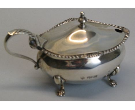 An Edwardian mustard pot, of oval form with urn finial on hinged domed lid with leaf capped scroll loop handle, blue glass li