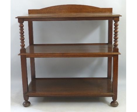 An early 20th Century oak buffet, having arched back over three tiers on bobbin turned and block supports, on flattened bun f