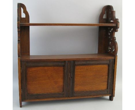 An early 20th Century walnut cupboard, wall mounting with pierced sides and single open shelf over two moulded doors, 60cm wi