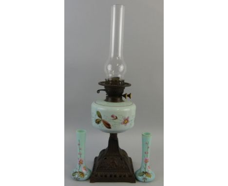 A Victorian table oil lamp, with cast and pierced iron pyramid shaped base supporting a floral painted opaque glass reservoir