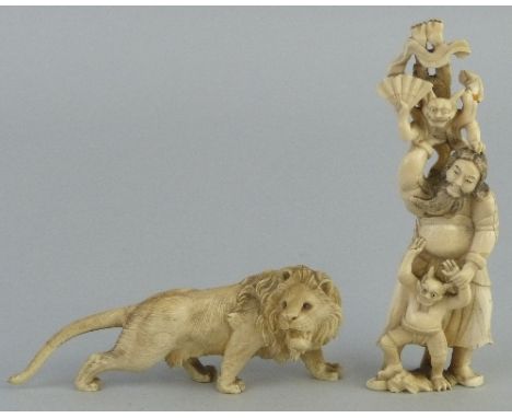 A Japanese ivory group, carved as a bearded man wearing a Samurai sword standing playing with two impish figures with horns, 