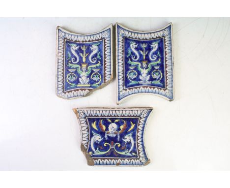 Three Continental ceramic tiles with glazed mythical style decoration on blue ground, with repeating leaf borders. (Complete 