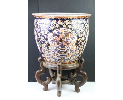 Large Chinese fish bowl planter, decorated in the Imari palette, with panels depicting flowers spilling from vases, on a coba