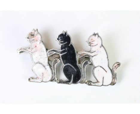 A silver plated and enamel brooch in the form of three seated cats. 