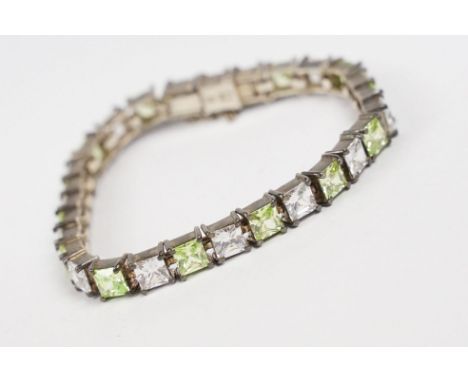 A contemporary 925 sterling silver tennis bracelet set with light green and clear stones, complete with safety chain, marked 