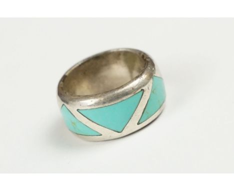 A 925 sterling silver band ring set with three flush turquoise stones of triangular form, marked 925 for sterling silver. 