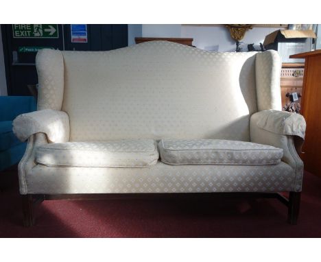 A Georgian mahogany wingback sofa, with cream upholstery, on reeded legs joined by stretchers, H.113 W.166 D.72cm 