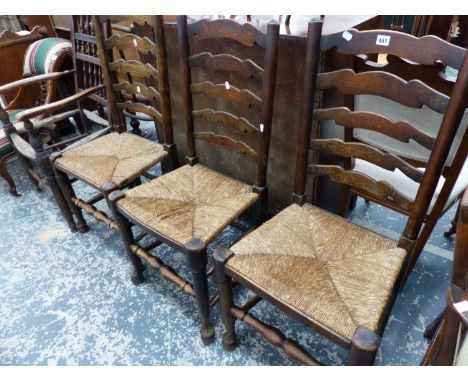 THREE RUSH SEAT LADDER BACK CHAIRS AND A SPINDLE BACK ARM CHAIR. 