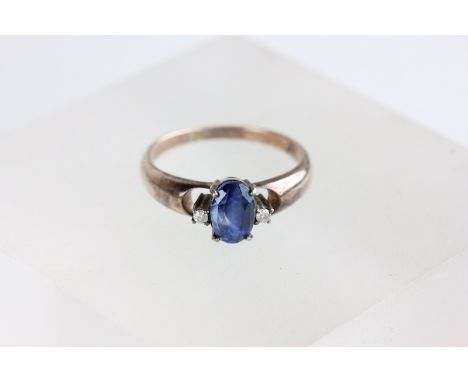 A three stone sapphire and diamond ring, the oval cut stone flanked by small brilliant cuts, finger size L1/2