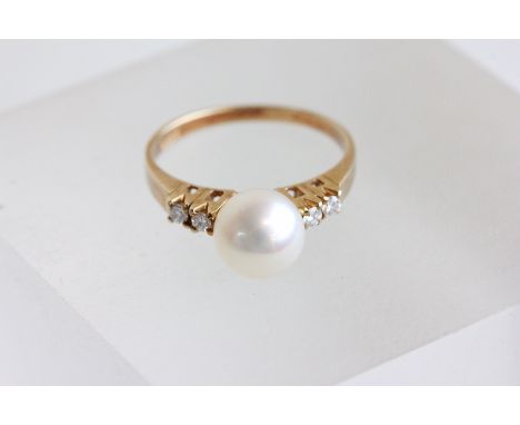 A Mikimoto cultured pearl and diamond ring, stamped '585', the pearl of approximately 7.7mm diameter, flanked by pairs of sma