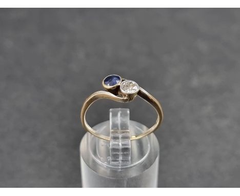 A yellow metal crossover ring,&nbsp;set brilliant cut diamond and faceted sapphire, stamped '18ct', size N. 