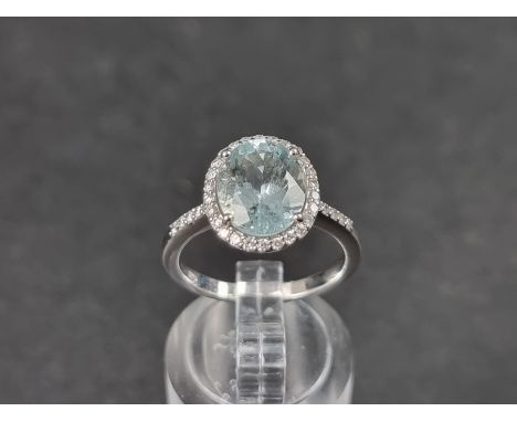 A white metal ring,&nbsp;set central faceted aquamarine of approx. 2.60ct, surrounded by small brilliant cut diamonds, with f