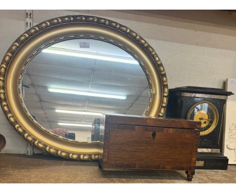 An oval gilt framed mirror, an early Victorian rosewood tea caddy and a French black slate and marble mantle clock