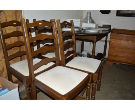 An oak dining table raised on turned legs together with a matching set of four ladder back chairs 