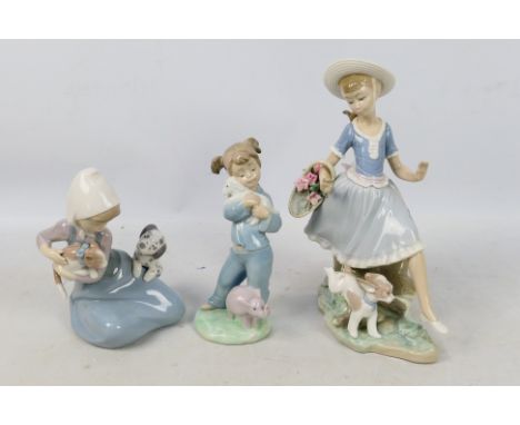 Three Spanish porcelain figures / groups by Lladro and Nao comprising Mirth In The Country # 4920, Little Friskies # 5032 and