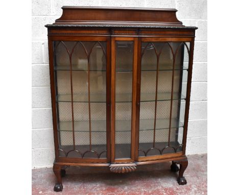 A 1920s walnut bowfront display cabinet with raised back above central bevelled glass panel flanked by two astragal glazed do