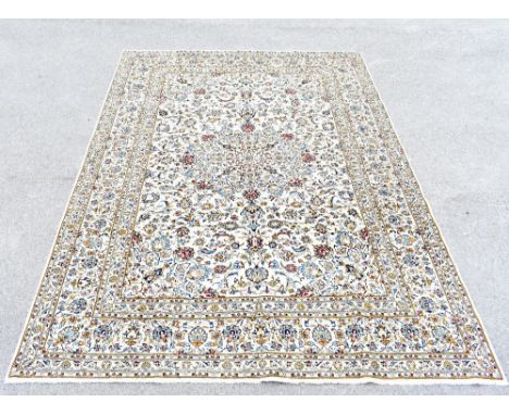 A Persian hand knotted wool Kashan carpet decorated with overall foliate motifs against a beige ground, 348 x 247cm.Additiona