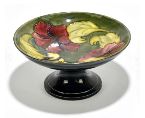 WALTER MOORCROFT; a comport decorated in 'Hibiscus' pattern on a green ground, green signature, impressed marks and Moorcroft